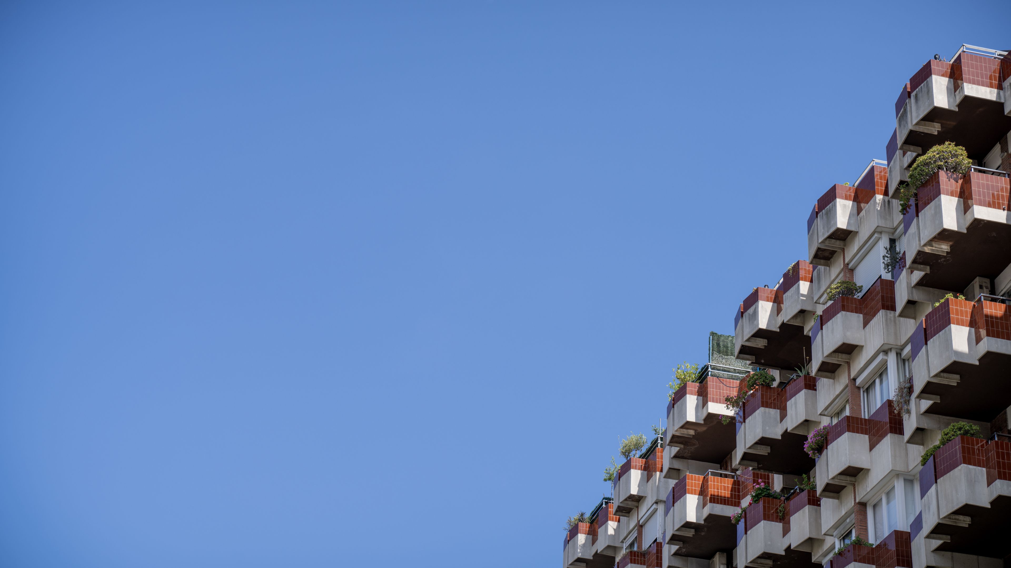 A modern residential building with protruding balconies against a clear blue sky.
