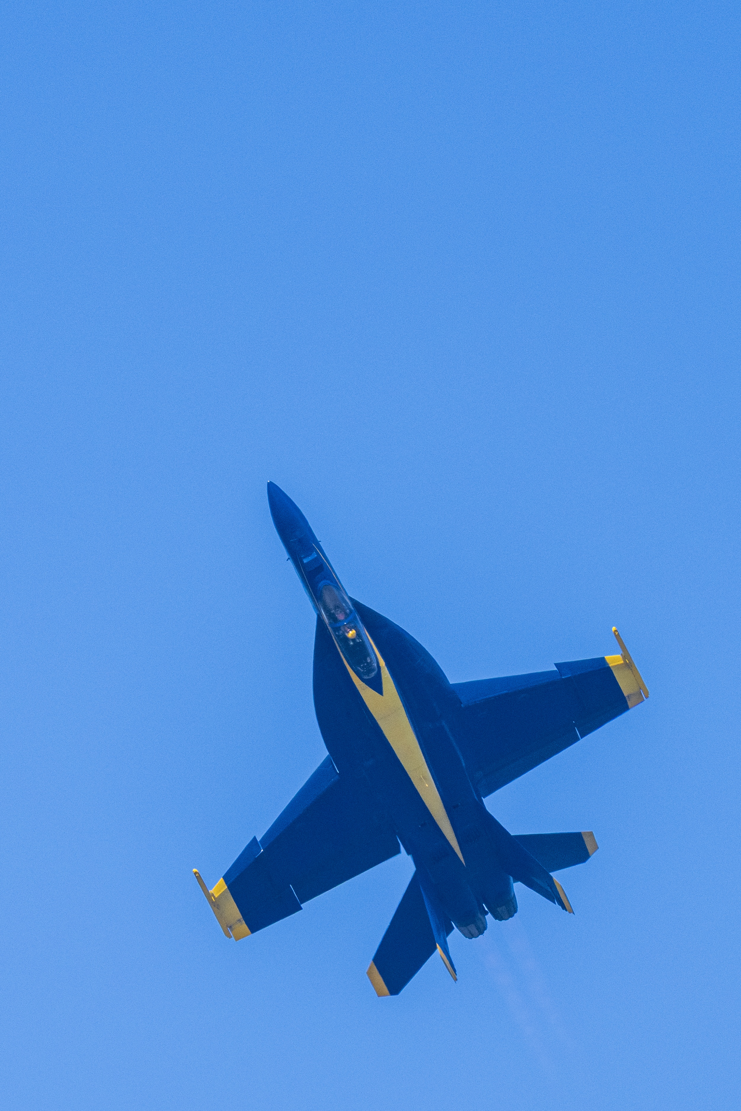 A close view of a Blue Angels jet's underside against blue sky.