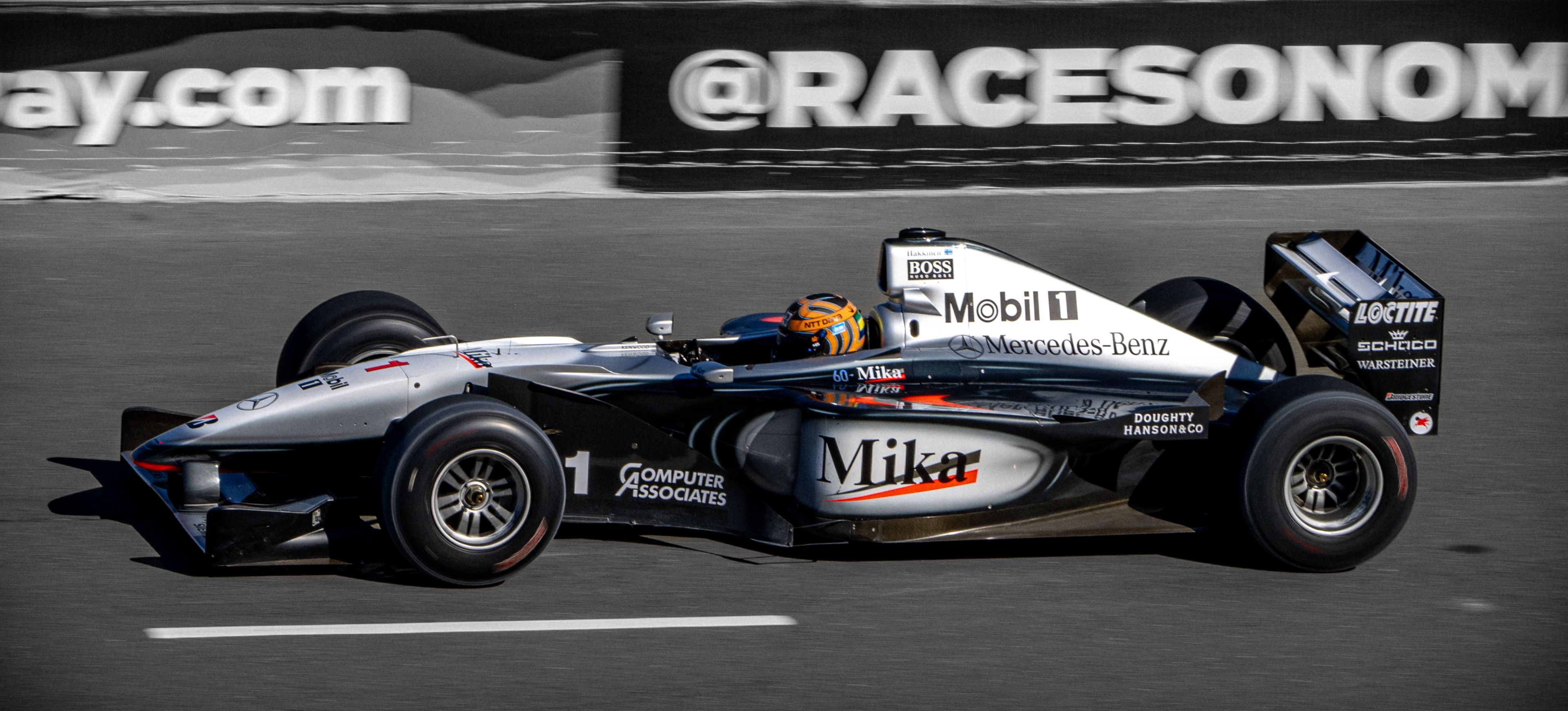 A silver race car speeds down the track during a motorsport event.