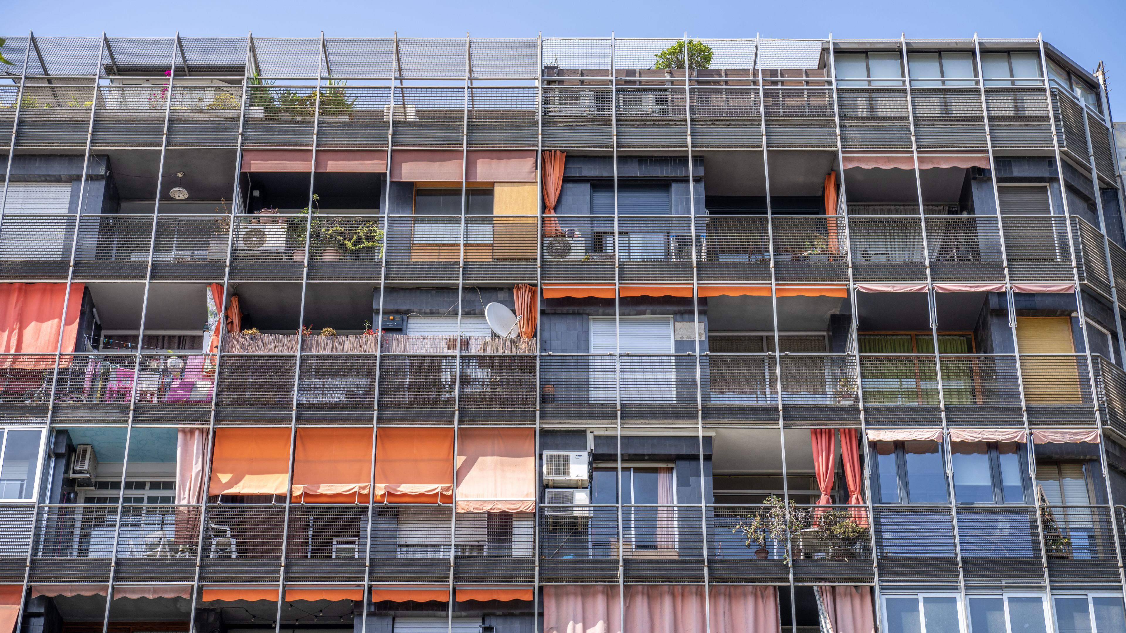 Multi-level apartment building features colorful balconies and greenery in Spain.